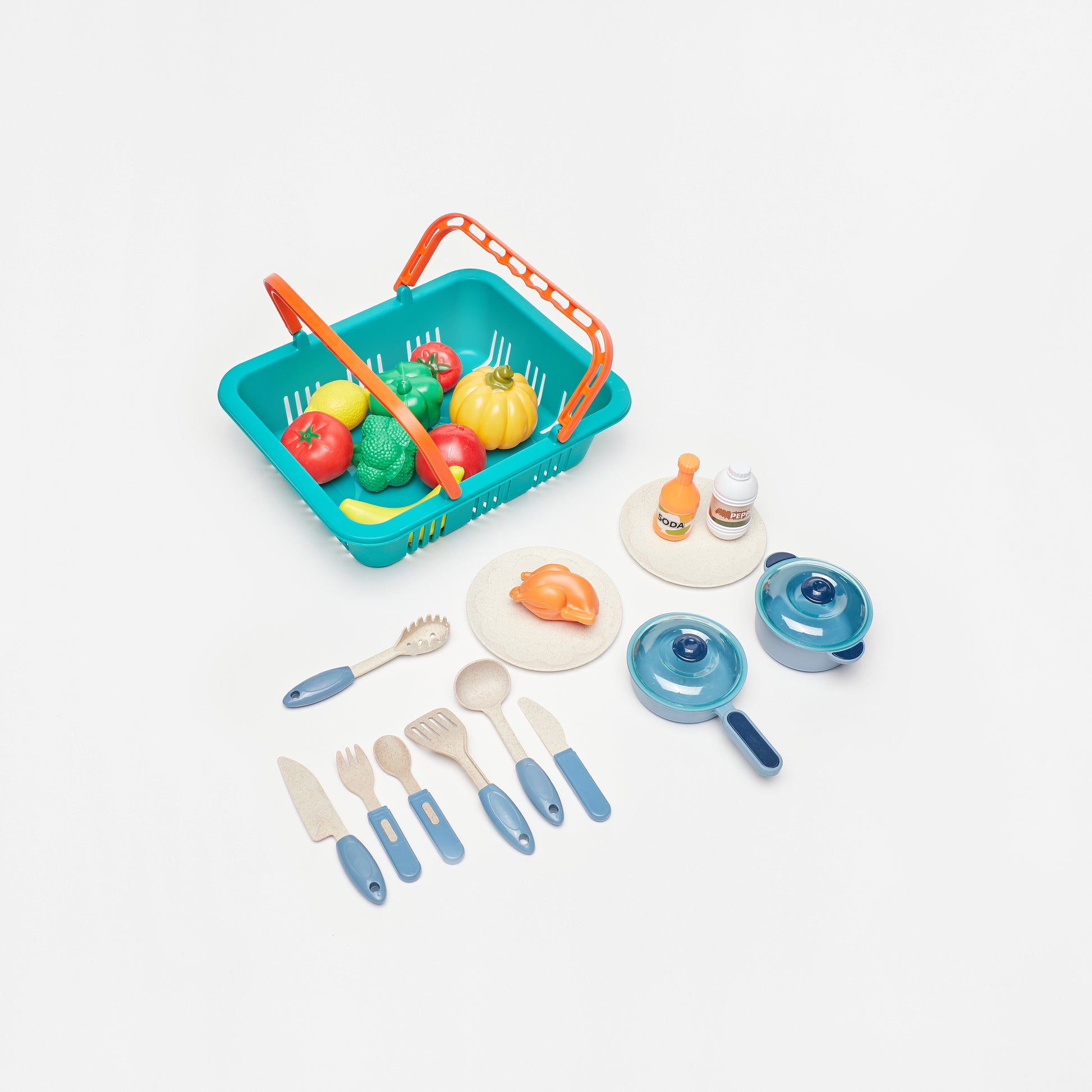 Set of toy kitchen items including a basket with fruits, utensils, and cookware on a white background